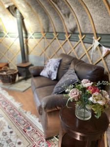 a living room with a brown couch and a table with flowers at Lovely 1 bed Yurt in Salisbury in Salisbury