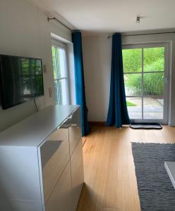 een woonkamer met een tv en een groot raam bij Le Jardin d'Isa in Chaumont-Gistoux