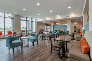 MainStay Suites Milwaukee-Franklin في فرانكلين: غرفة انتظار مع طاولات وكراسي ونوافذ