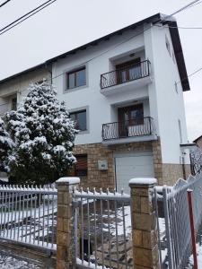 a white house with a fence and a tree at Villa Amer Lux Apartments in Sarajevo