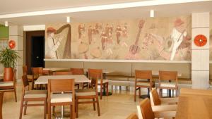 a restaurant with tables and chairs and a large mural at Hotel Morúa in Yopal
