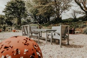 three chairs and a table in a park with trees at Higher Trewithen in Stithians