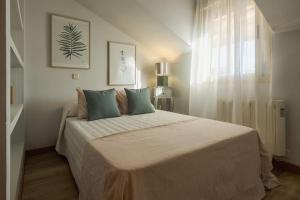 een witte slaapkamer met een groot bed met blauwe kussens bij Apartamento de diseño in Alcalá de Henares