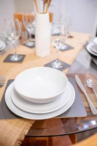 een tafel met witte borden en wijnglazen erop bij Charming 1-Bedroom Just 1 Mile from Morley Town Center in Leeds in Pudsey