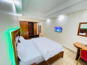 a bedroom with a bed and a desk and a tv at Pulickal Heights Hotel in Entebbe
