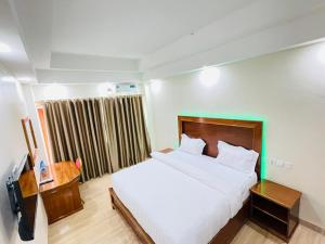 una camera da letto con un grande letto bianco e una finestra di Pulickal Heights Hotel a Entebbe