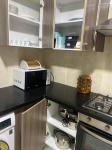 Il comprend une cuisine équipée d'une cuisinière et d'un four micro-ondes. dans l'établissement Superbe appartement hautstanding, à Sfax