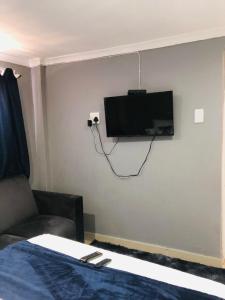 Cette chambre dispose d'un canapé et d'une télévision murale. dans l'établissement Rose-Lee Cottage, à Durban