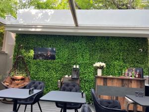 a green wall with tables and chairs in a restaurant at La Vila Maria in Bucharest