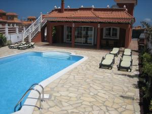 een zwembad met ligstoelen en een huis bij Verano Brisa Private Golf Villa in Caleta De Fuste