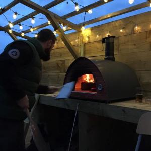 a man is standing next to a brick oven at Easter Ellister in Port Charlotte