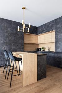 a kitchen with a counter and two chairs and a chandelier at Rent like home - Apartament w Deo Plaza in Gdańsk