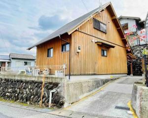 a large wooden house on a stone wall at 飲食店やスーパーも徒歩圏内！豊かな自然と共存するウッドハウス。 