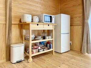 a kitchen with a microwave on a shelf next to a refrigerator at 飲食店やスーパーも徒歩圏内！豊かな自然と共存するウッドハウス。 