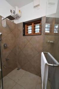 baño con ducha y puerta de cristal en Chembra Adobe Pattanimala Kerala, en Kalpetta