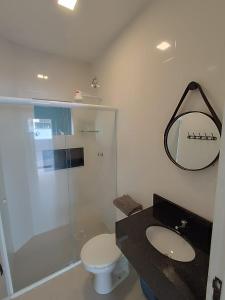 a bathroom with a toilet and a sink and a mirror at Residencial Brisa do Mar 2 in Bombinhas