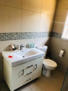 een badkamer met een witte wastafel en een toilet bij Rose-Lee Cottage in Durban