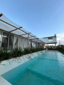 a swimming pool next to a building with blue water at Malujoseignacio in José Ignacio +33 photos