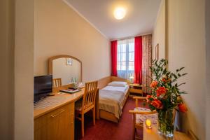 a hotel room with a desk with a computer and a bedroom at Hotel Gromada Toruń in Toruń