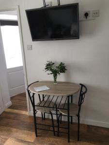 a table and a chair with a vase on it at Little Owl Self Catering in Little Barningham