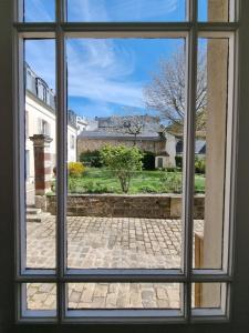 een open raam met uitzicht op een binnenplaats bij Charmant studio proche du château in Versailles