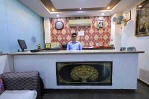 a man standing behind a counter in a room at Hotel Orchid & Banquet in Agra