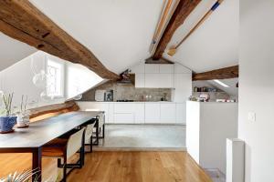 an attic kitchen with white cabinets and a wooden floor at Pretty Parisian Penthouse in Paris +16 photos