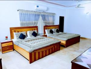 a bedroom with two beds and a window at Galaxy Inn Guest House in Karachi