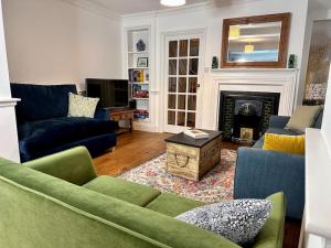 a living room with a green couch and a fireplace at Cathedral Views Period Townhouse w/ Free Parking in Salisbury