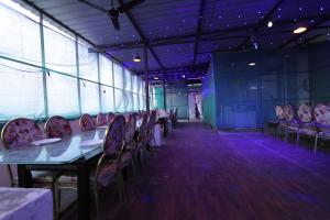 a dining room with tables and chairs with purple lights at Hotel Orchid & Banquet in Agra