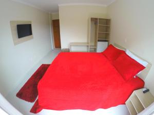 1 dormitorio con cama roja y almohadas rojas en Pousada Magnus, en Balneário Camboriú