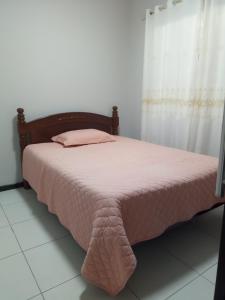 a bed in a room with a pink blanket on it at Casa de férias 2 quartos in Penha