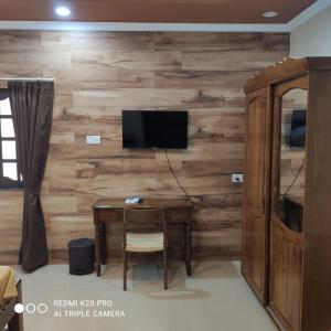 Habitación con pared de madera, mesa y TV. en Casa Coutinho, en Porvorim