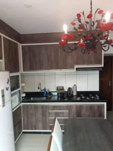 a kitchen with wooden cabinets and a chandelier at Casa de férias 2 quartos in Penha