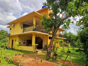 uma casa amarela com uma árvore em frente em Nature Paradise Guesthouse em Wayikkal