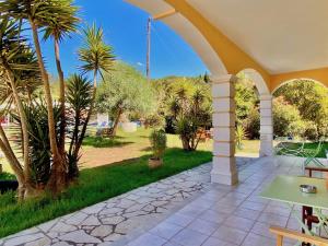 a patio with an archway with palm trees and a yard at Pangea Corfu Villa in Sidari