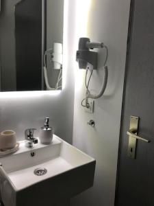 a bathroom with a white sink and a mirror at The Grey Apartment - Center of Prishtina in Pristina