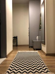 a hallway with a black and white rug on a wooden floor at The Grey Apartment - Center of Prishtina in Pristina