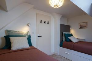 a bedroom with two beds and a white door at Calme, Confort et Propreté in Vittel