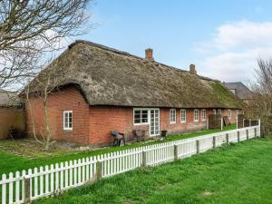 une maison en briques avec un toit de chaume et une clôture blanche dans l'établissement Apartment Grethel - all inclusive - in Western Jutland by Interhome, à Højer