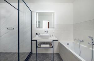 a white bathroom with a sink and a shower at Hotel New York by WestCord in Rotterdam
