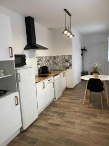 a kitchen with white cabinets and a table in it at Studio bien situé & tout équipé dans une maison in Scionzier