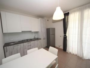 uma cozinha com armários brancos e uma mesa e cadeiras brancas em Apartment Veranda-6 by Interhome em Rosapineta