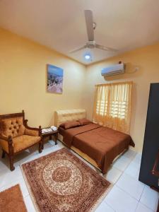 a bedroom with a bed and a fan and a rug at WawAmir Homestay @ Seri Iskandar in Seri Iskandar