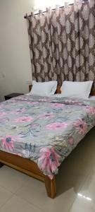 a bed with a floral comforter and a headboard at Brookside Service Apartment in Bangalore
