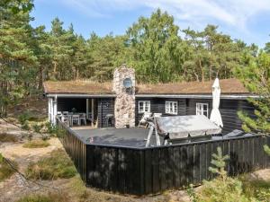 uma casa com um grande deque na floresta em Holiday Home Solfred - 200m from the sea in Bornholm by Interhome em Vester Sømarken