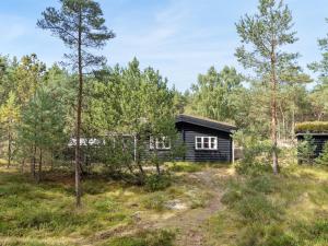 a cabin in the woods with trees at Holiday Home Solfred - 200m from the sea in Bornholm by Interhome in Vester Sømarken