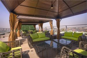 un patio con sillas verdes y mesas en el techo en GTA HOTEL IKEJA en Ikeja