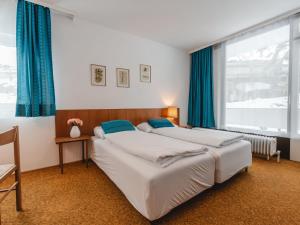 2 Betten in einem Schlafzimmer mit blauen Vorhängen und einem Fenster in der Unterkunft Apartment Alpenpanorama by Interhome in Bad Gastein