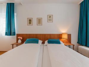two beds in a bedroom with blue curtains at Apartment Alpenpanorama by Interhome in Bad Gastein
